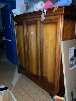 une armoire en bois au milieu d'une pièce, avec des cartons posés par terre