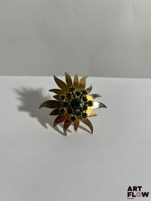 Gros plan sur une bague en or ornée de pierres vertes