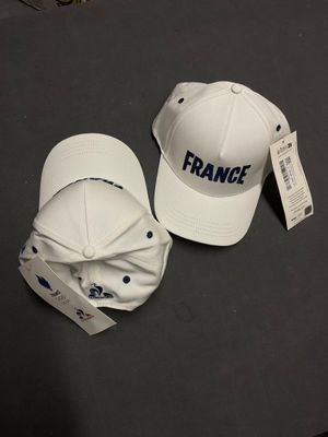 une paire de casquettes de baseball blanches portant l'inscription « France », posées sur une table