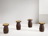 trois tabourets en bois sont posés sur une surface blanche devant un mur blanc