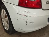 a white car that has been damaged and is parked in a garage
