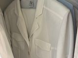 a lot of white shirts hanging on a rack in a closet