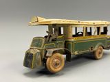 un petit bus jouet vert et jaune posé sur une surface blanche