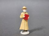 a figurine of a man in a yellow coat and hat holding a red folder