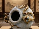 un vase blanc orné d'un dragon, posé sur un socle