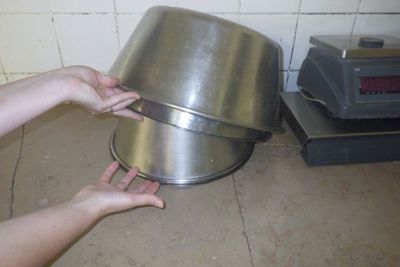 une personne tenant une grande poêle en métal au-dessus d'une cuisinière