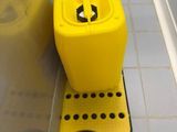 a yellow container sitting on the floor next to a toilet