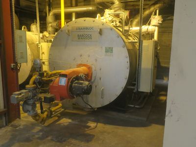 a picture of a boiler in a building with pipes and valves