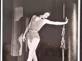 black and white photograph of a woman in a bathing suit holding onto a pole