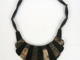 a close up of a black and gold necklace on a white background