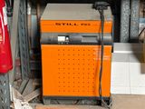 une machine orange posée sur une palette à côté d'un extincteur
