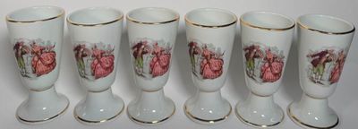 quatre vases ornés de fleurs peintes sont alignés sur une surface blanche