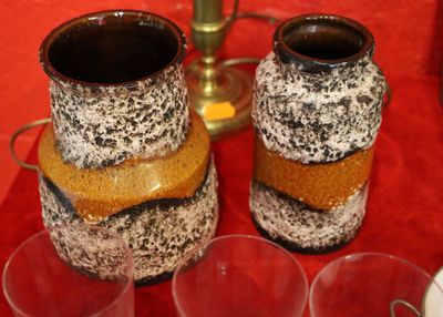 two vases that are sitting on a table with cups