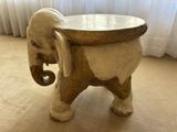 an elephant stool sitting on the floor in front of a window