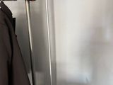 a red suitcase sitting on the floor next to a coat rack