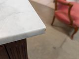 a white marble counter top with a pink chair in the background