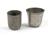 two silver cups sitting next to each other on a white surface