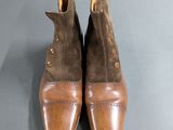 pair of brown sued shoes with brown leather soles on a gray surface