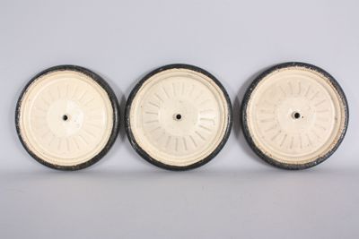 three white and black wheels sitting on top of a white surface