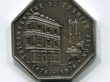 une pièce d'argent sur laquelle figure l'image d'un bâtiment