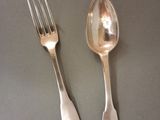 two silver spoons and a fork on a table