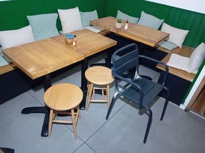 des tables et des chaises dans une alcôve aux murs verts et aux coussins blancs