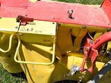 a yellow and red cart with a red handle on the grass