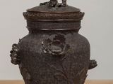 an antique bronze urn with a bird on top on a table