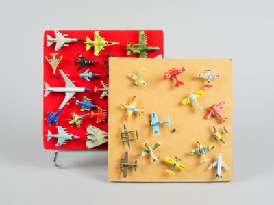 de nombreux petits avions miniatures posés les uns à côté des autres sur une surface rouge