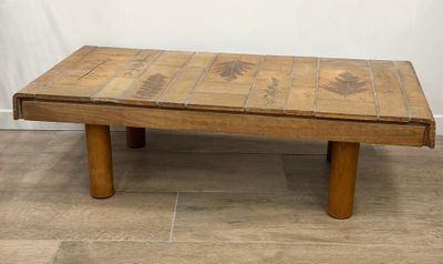 une vieille table basse en bois avec un plateau en carrelage, posée sur un sol carrelé