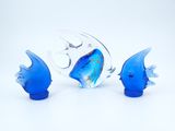 three blue glass fish figurines sitting on a white surface