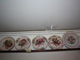 five plates on a shelf that have flowers painted on them