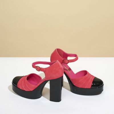 des chaussures à talons hauts roses et noires posées sur une surface blanche