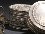 une boîte en argent et une figurine en argent posées l'une à côté de l'autre