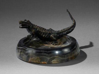 statue d'un lézard posée sur un socle en marbre, sur une surface grise