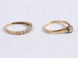 two gold rings with diamonds on them on a white surface