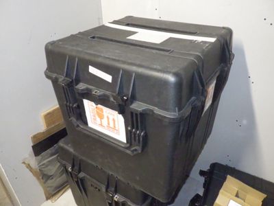 une valise noire posée au sommet d'une pile de cartons