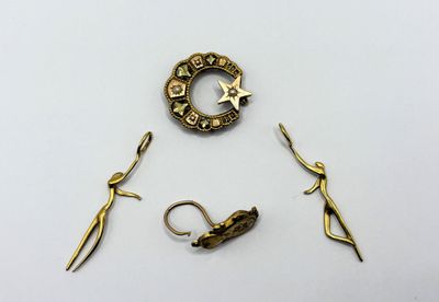 three pieces of jewelry including a star, a ring, and a pair of scissors