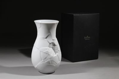 un vase blanc orné d'un motif craquelé, posé à côté d'une boîte noire