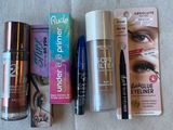 Divers produits de maquillage sont alignés sur une surface blanche