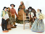 five figurines of people standing next to a chair