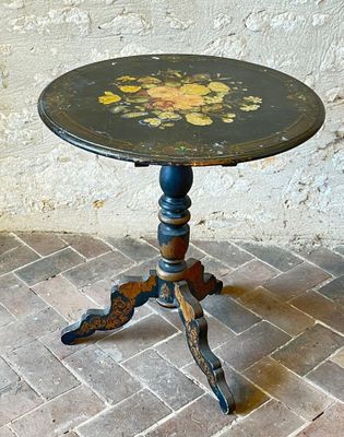 a small table with a painted top on a brick floor