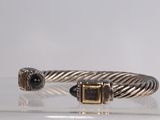 cable bracelet with black stones and gold accents on clear surface