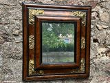 un miroir accroché à un mur de pierre, avec un arbre en arrière-plan