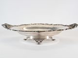 a silver bowl with a handle on a stand on a white surface