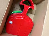 a red plastic bottle in a cardboard box with a green handle
