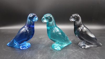 three glass birds sitting on top of a table next to each other