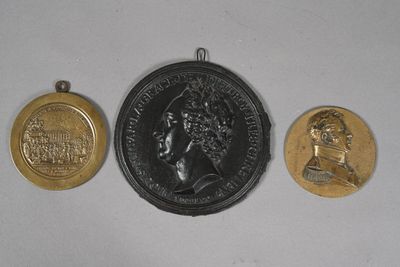 three gold and silver medallions of a woman and a man