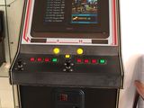 a small game machine sitting in a room next to a chair