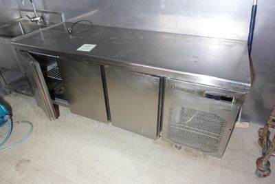 une cuisine en acier inoxydable équipée d'un évier et d'un réfrigérateur
